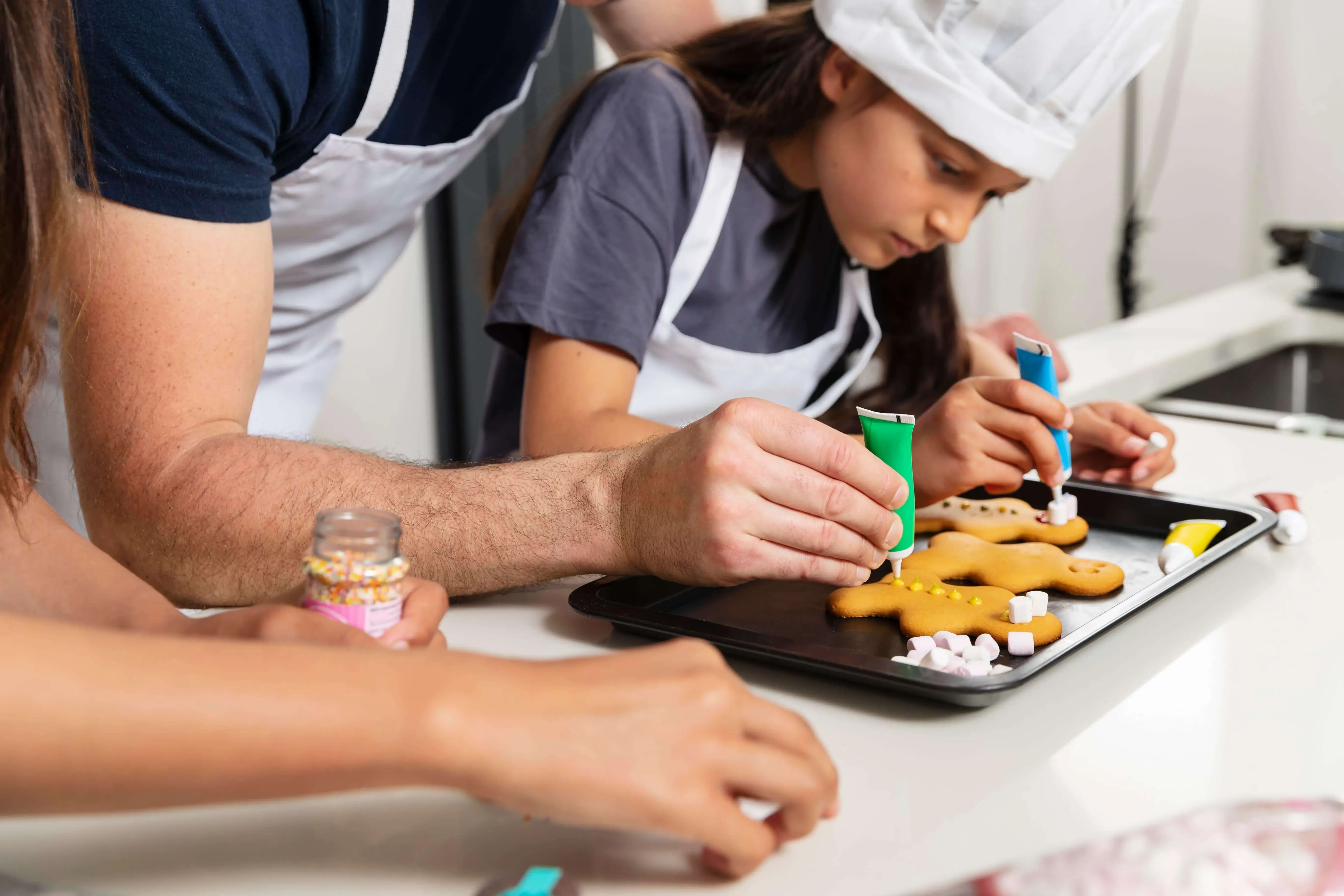 Family baking class with parent and children decorating cookies together